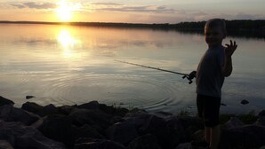 Un niño pescando en un lago tranquilo al atardecer.