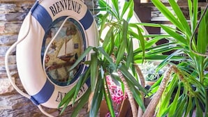 Una boya con el texto "BIENVENUE ENCORE", un muro de piedra y plantas verdes.