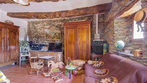 Una sala rústica con pared de piedra, muebles de madera, un televisor y un globo terráqueo.