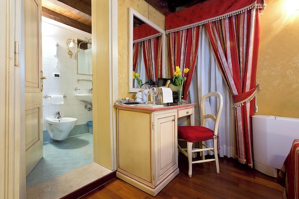 A bathroom with a sink, mirror, and a chair with a red cushion. - Ca' San Polo - Ferretti Hotels Collection (Venice)
