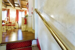 A staircase with a red carpet leading to a room with wooden flooring, a white wall, and a red curtain. - Ca' San Polo - Ferretti Hotels Collection (Venice)