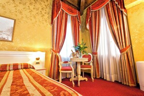 A hotel room with a bed, two chairs, a table with a vase, and curtains. - Ca' San Polo - Ferretti Hotels Collection (Venice)