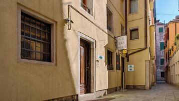 A narrow street with buildings on either side, a sign for 'Ca' San Polo,' and a visible door entrance.