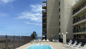Ein Pool auf dem Dach mit Liegestühlen und Blick auf den Ozean.
