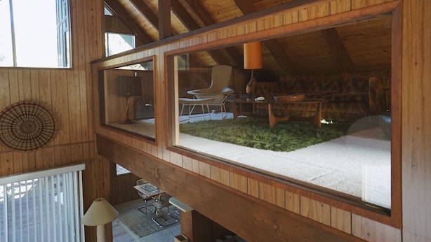 A high-ceilinged wooden room with a large window, a chair, and a table. - 1970s Architecture & Design Cabin - The Lone Pine (Frazier Park)