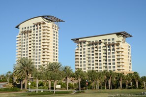 Two high-rise buildings with balconies, surrounded by palm trees and a clear sky. - Lockout Unit ~ Near the Beach ~ Gulf Views ~ Resort Pool (Miramar Beach)