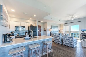 A modern kitchen with a large island, bar stools, and a dining area with a view.