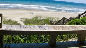 A beach view from a wooden deck with a clear sky and ocean. - Catalina Spectacular Oceanfront  4BR 4BA Duplex Addition & Major Renovation 2025 (Emerald Isle)
