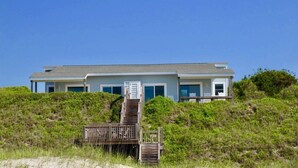 A two-story house with a wooden staircase leading up to a deck. - Catalina Spectacular Oceanfront  4BR 4BA Duplex Addition & Major Renovation 2025 (Emerald Isle)