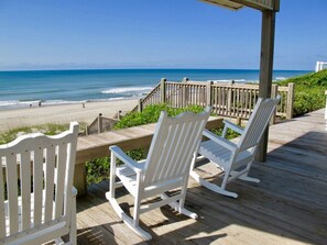 A wooden deck with white rocking chairs overlooking a beach. - Catalina Spectacular Oceanfront  4BR 4BA Duplex Addition & Major Renovation 2025 (Emerald Isle)