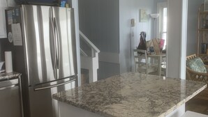 A modern kitchen with a stainless steel refrigerator, white cabinetry, and a granite countertop. - Catalina Spectacular Oceanfront  4BR 4BA Duplex Addition & Major Renovation 2025 (Emerald Isle)