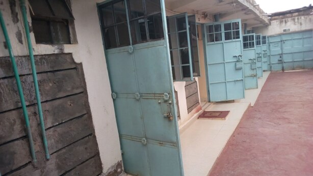 A row of blue doors with a tiled floor and a concrete wall. - Mumbi Rose Guest House (Thika)