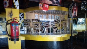 A circular structure with a yellow and black color scheme, a fire extinguisher mounted on the wall, and a sign with the word "TUSK". - Mumbi Rose Guest House (Thika)