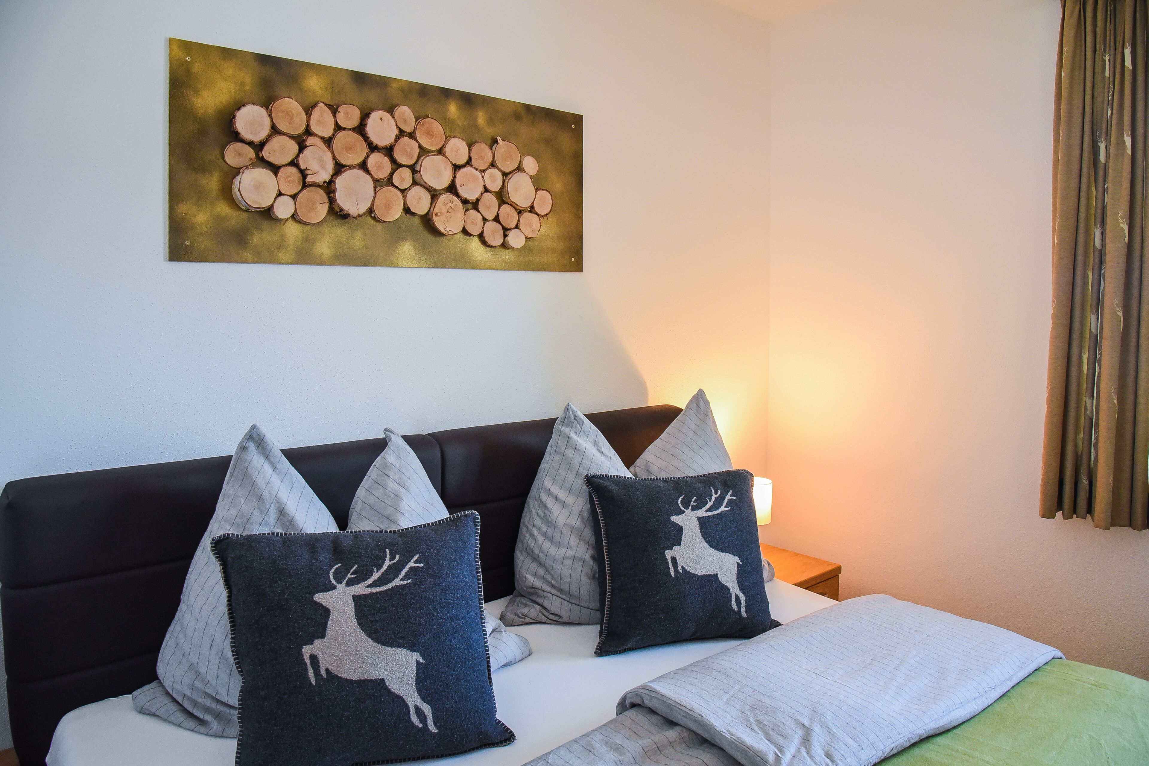 Un dormitorio con una cama, almohadas, cabecero, una obra de arte en la pared y una mesita de noche.