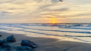 A beach with waves, rocks, and a sunset. - Spectacular sunrise and ocean views! Award winning "Best Condo Rentals!" (Galveston)