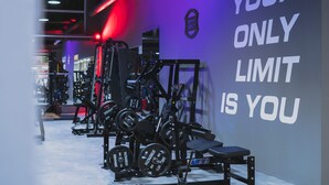 Et fitnesscenter med vægttræningsudstyr og motiverende tekst på væggen.