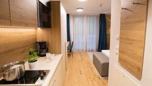 Et moderne køkken med træskabe, en indbygget mikroovn og komfur. Der er et spiseområde med bord og stole, samt en lille siddekrog med en sofa.