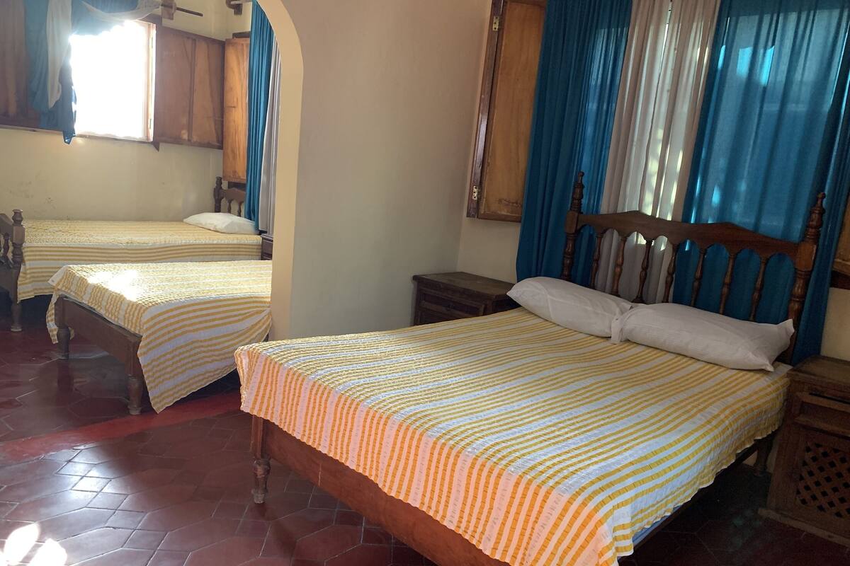 A hotel room with two beds, wooden headboards, and a tiled floor.