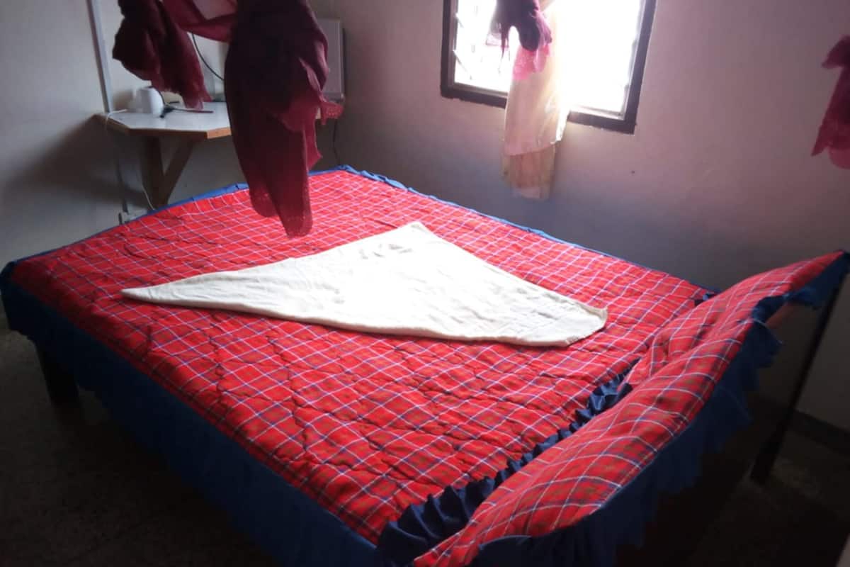 A bed with a red and blue checkered bedspread and a white blanket.