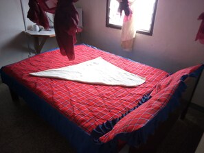 A bed with a red and blue checkered bedspread and a white blanket.