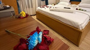 A bedroom with a bed, curtains, a painting, and a decorative flower arrangement. - Golden Palace Hotel (Cairo)