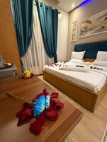 Une chambre à coucher avec un lit, des rideaux, un tableau et un arrangement floral décoratif.