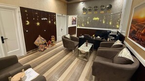 A hotel lobby with a reception desk, seating area, clocks, and decorative wall panels. - Golden Palace Hotel (Cairo)