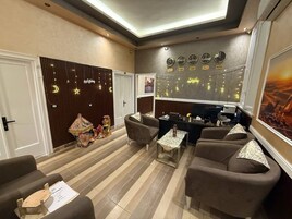 Un hall d’hôtel comprenant un comptoir d’accueil, un espace salon, des horloges et des panneaux muraux décoratifs.