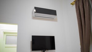A room with a white wall, a mounted air conditioner, and a flat-screen TV. - Golden Palace Hotel (Cairo)