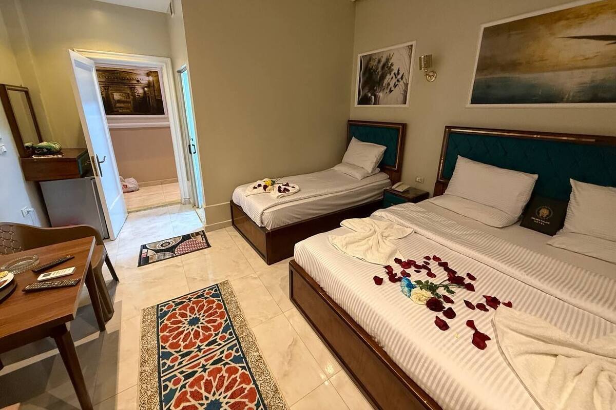 A hotel room with two beds, a dining area, and a bathroom.