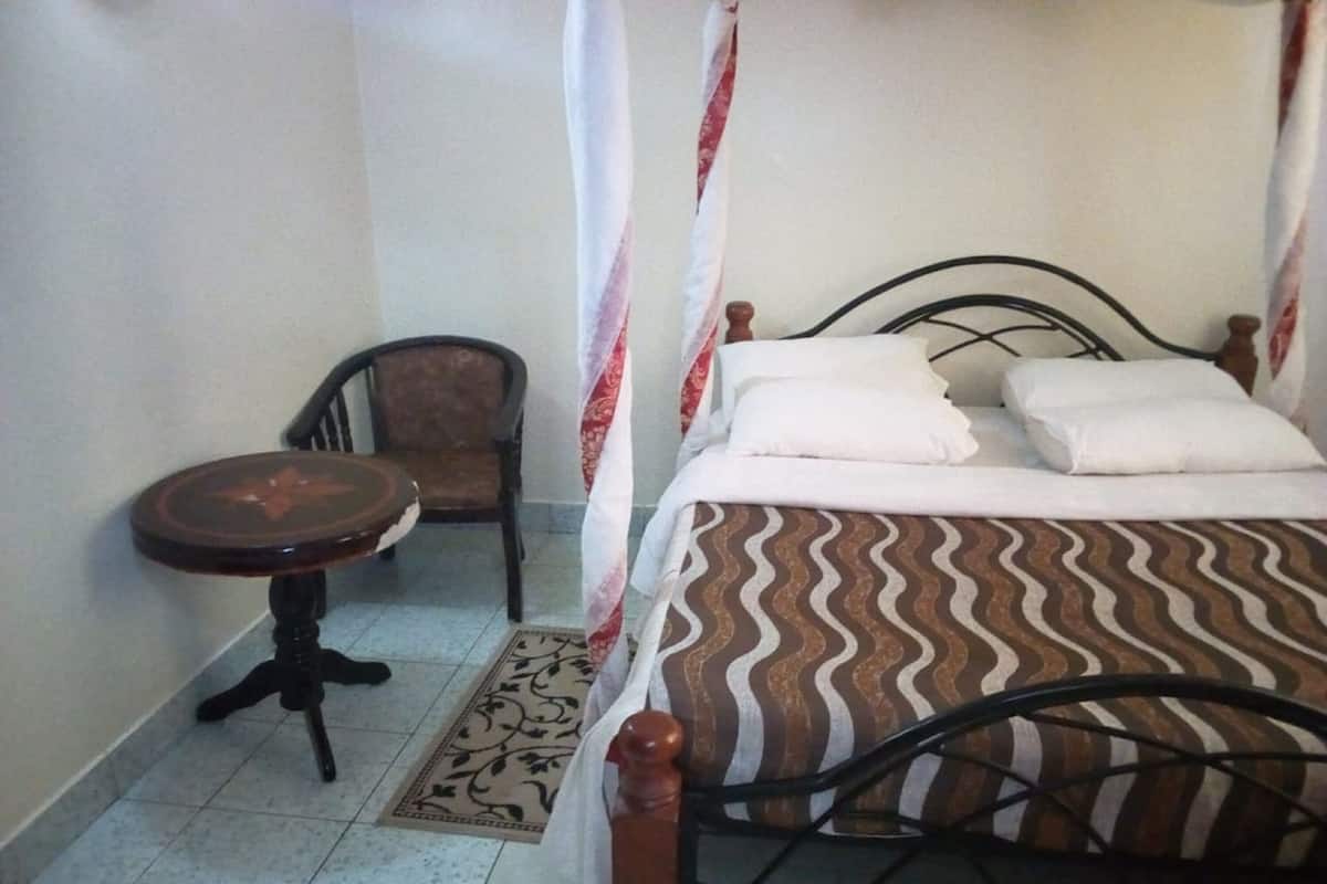 A small, neatly arranged bedroom with a bed, a chair, and a small table.