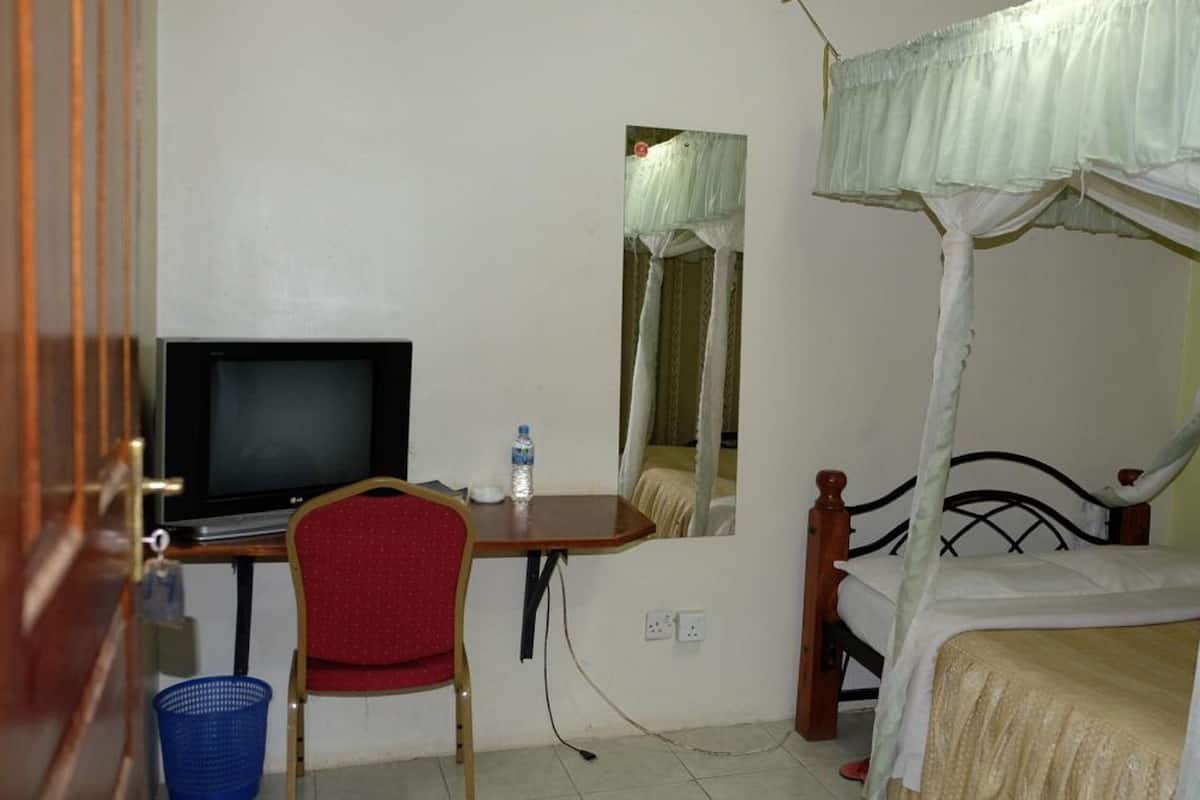 A bedroom with a bed, a television, a desk, and a chair.