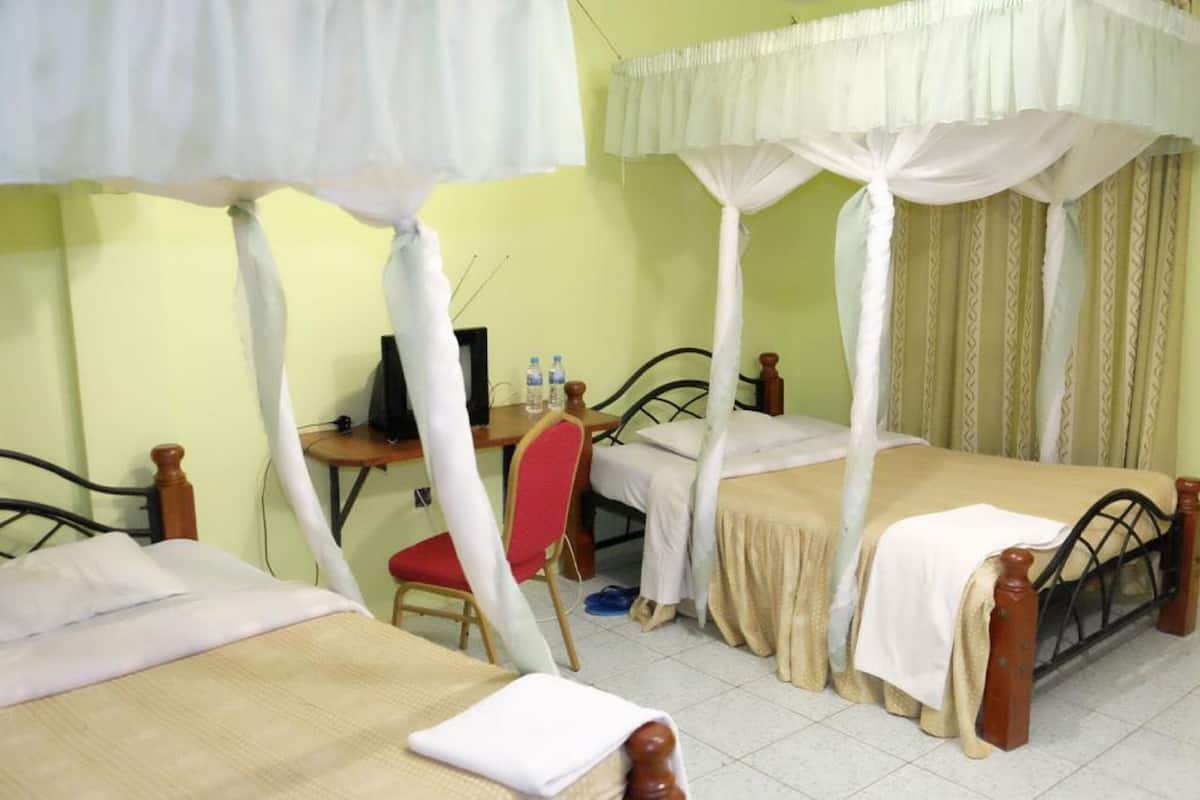 A room with two beds, a desk, a chair, and a computer.