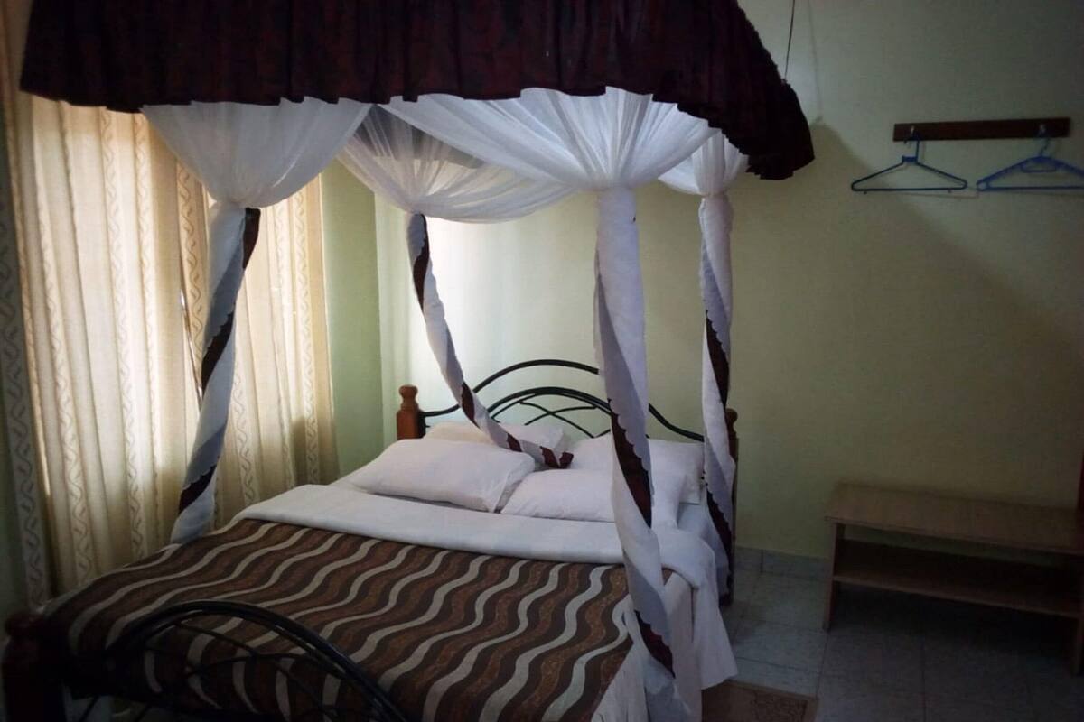 A bed with a canopy, a bedside table, and a wall-mounted hanger.