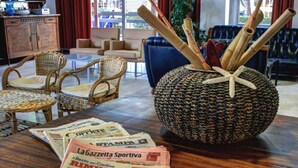 Una habitación con muebles de mimbre, un centro de mesa tejido y periódicos sobre la mesa.