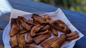 A plate of fried plantains on a wooden table.