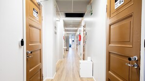 A hotel hallway with wooden doors, a white reception desk, and a sign indicating room 12. - Vanha Postitalo (Varkaus)