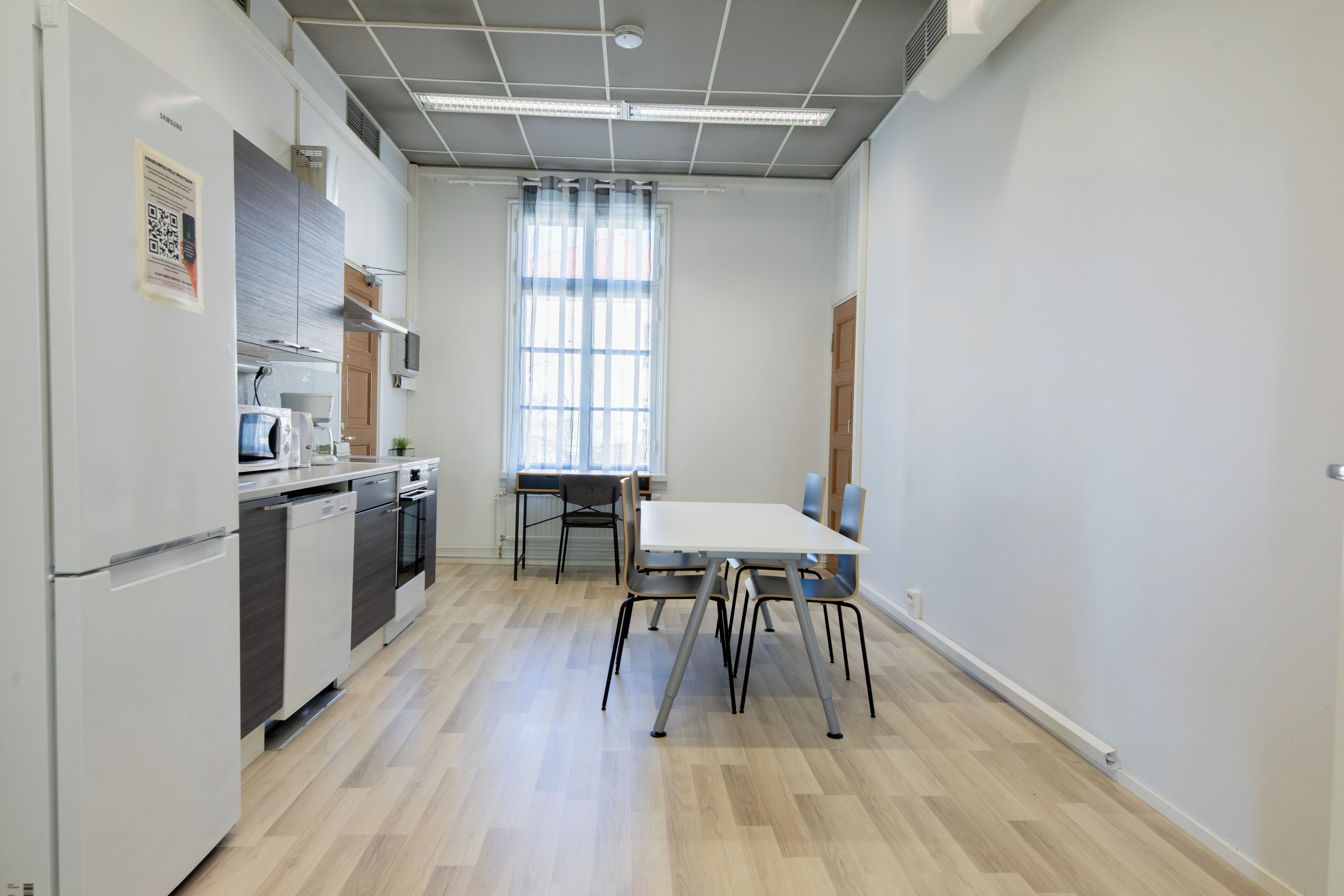 Une cuisine moderne équipée d’une table et de chaises, d’un réfrigérateur, d’un four à micro-ondes et d’un lave-vaisselle.