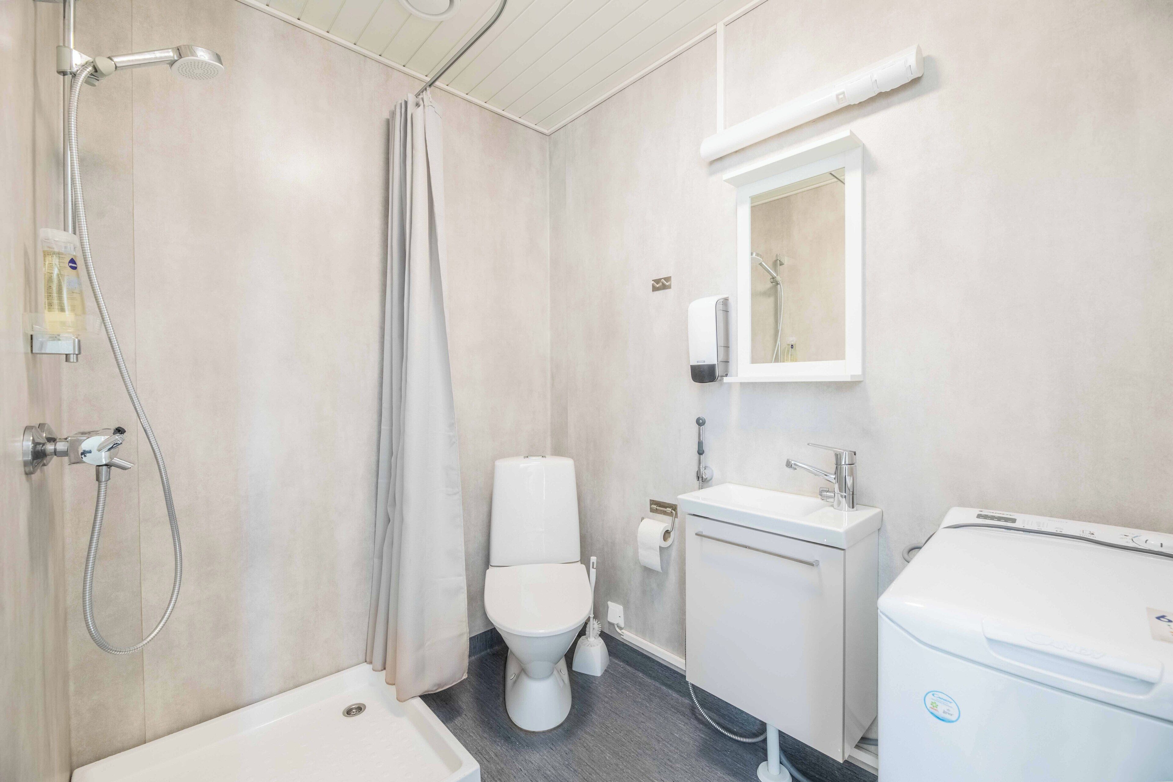 Un baño moderno con ducha, inodoro, lavamanos y espejo.