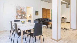 A modern living room with a dining area, featuring a white table, black chairs, a grey sofa, and a coffee table. - Vanha Postitalo (Varkaus)