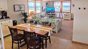 Un espacio habitable compacto con comedor, sofá, televisor y vista al océano.