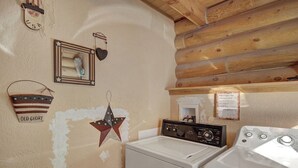 A laundry area with a washing machine and dryer, wooden ceiling, and wall decorations including a star and a heart. - Cook Family Lodge (Breckenridge)