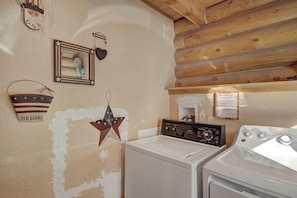 A laundry area with a washing machine and dryer, wooden ceiling, and wall decorations including a star and a heart.