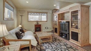 A cozy living room with a sofa, a coffee table, a fireplace, and a television. - Cook Family Lodge (Breckenridge)