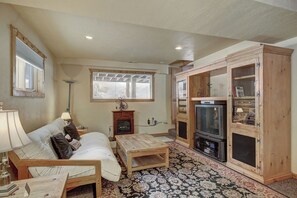 A cozy living room with a sofa, a coffee table, a fireplace, and a television.