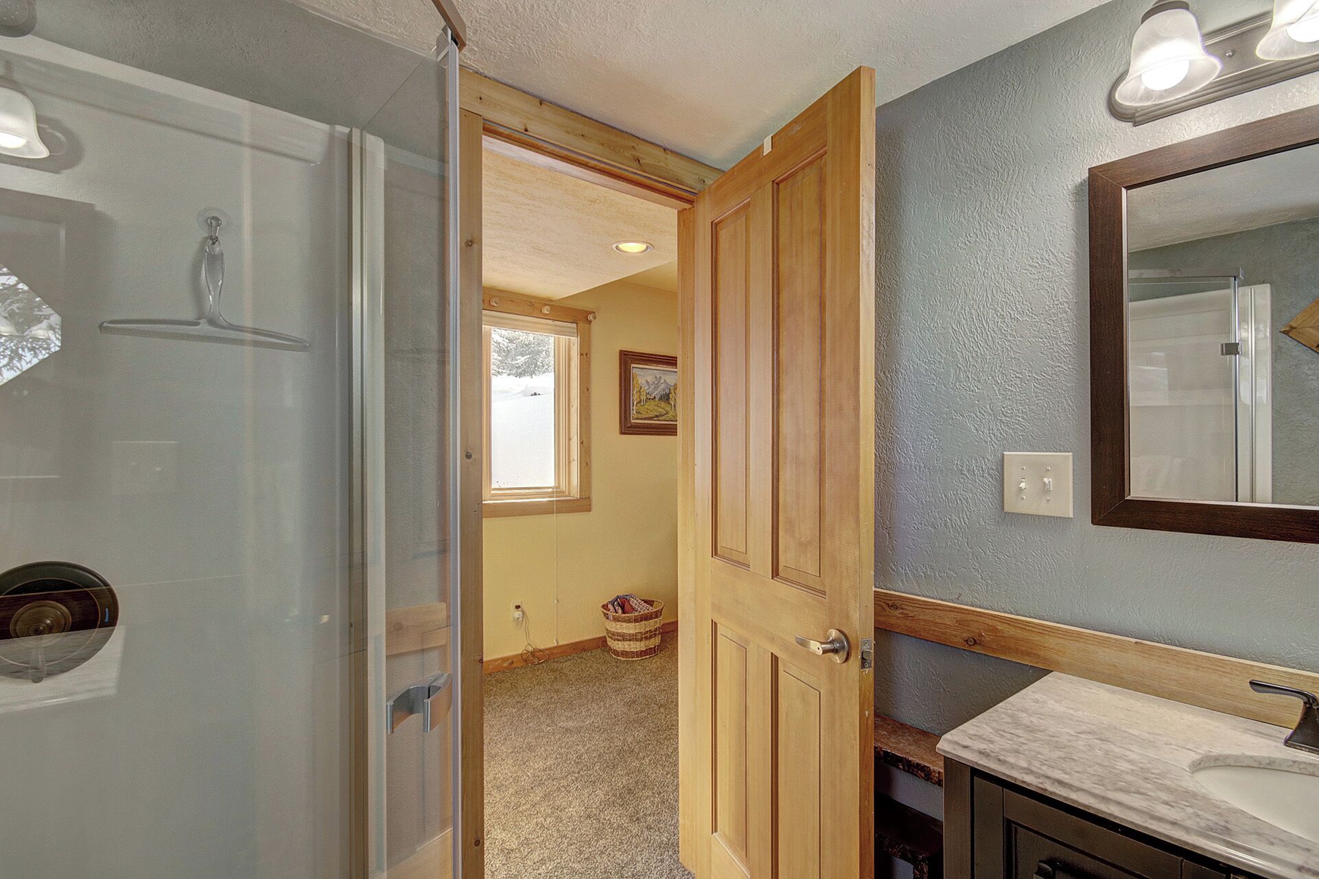 A bathroom with a shower, a sink, and a mirror.