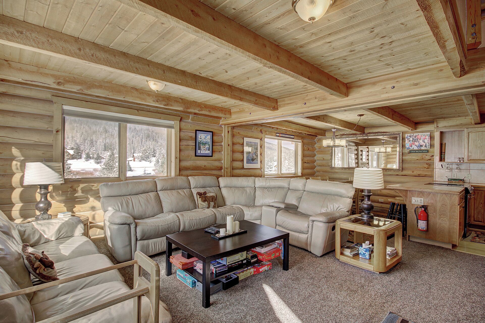 A log cabin interior with a sectional sofa, a coffee table, and a small side table.