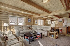 Ein Holzblockhaus-Interieur mit einer Eckcouch, einem Couchtisch und einem kleinen Beistelltisch.