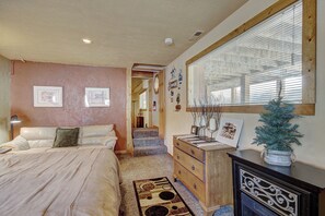 A bedroom with a bed, dresser, and a window with blinds. - Cook Family Lodge (Breckenridge)