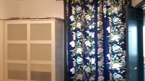 Un dormitorio con cama, armario, puerta y cortina de estampado floral.